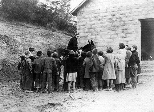 A librarian on horseback delivering books to a group of children