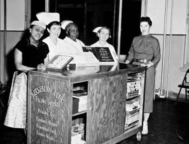 Black and white photo of nurses at a library cart at Seaview TB hospital in Staten Island