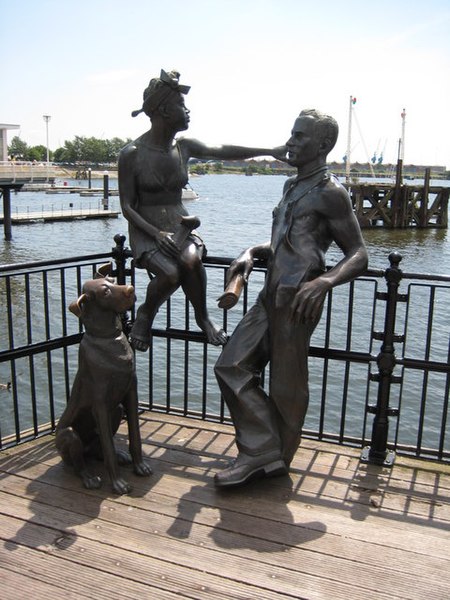 A bronze statue of a couple and dog symbolizing the arrival of immigrants to Tiger Bay