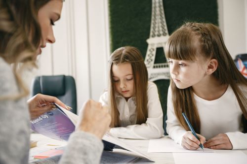 Woman holding book in front of two young girls