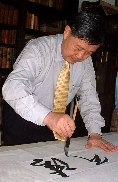 Chinese calligrapher Sun Xinde creating calligraphy on paper with an ink brush