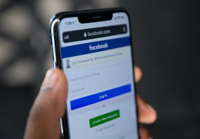 Person's hand holding phone showing Facebook login screen