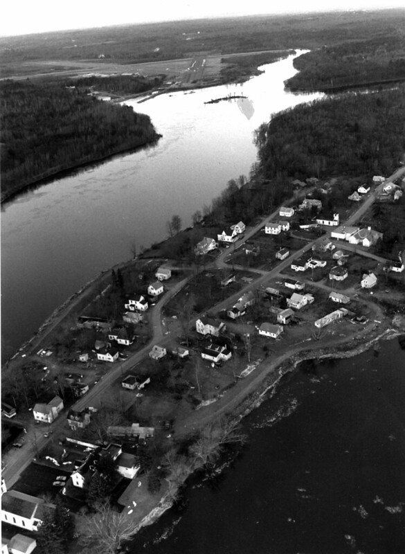 Black-and-white aerial photograph of the Penobscot Indian Reservation along the Penobscot River, trees and rooftops visible on land with surrounding water
