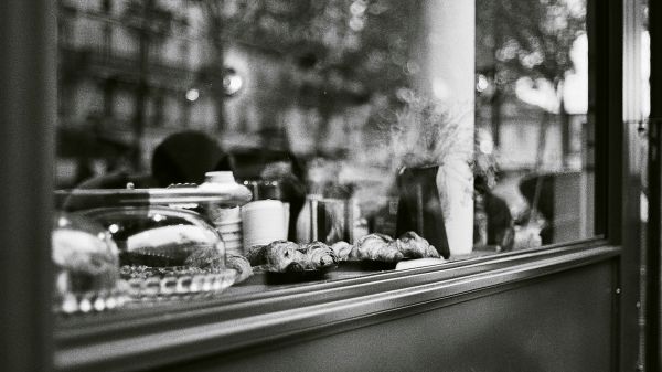 Black and white view of a window from outside with pastries on the sill