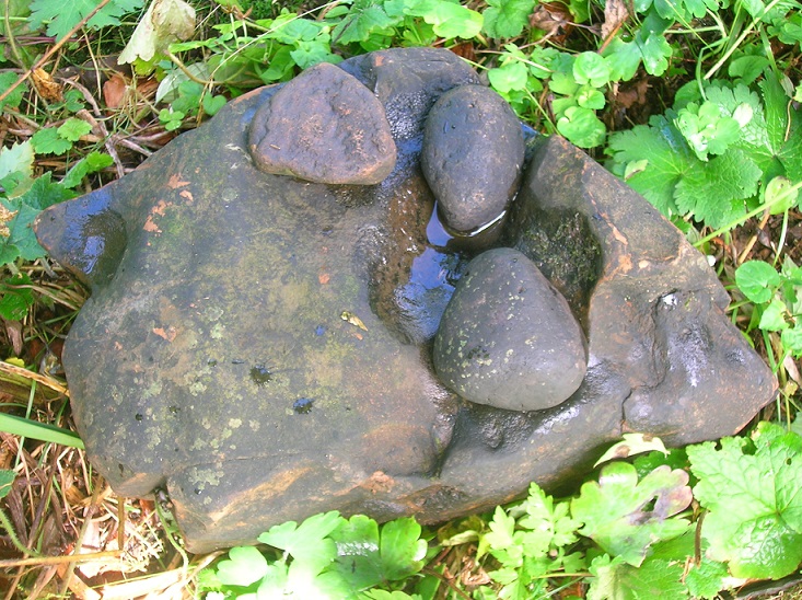 Ballaun featuring three smaller stones sitting in the depression of a larger flat stone 