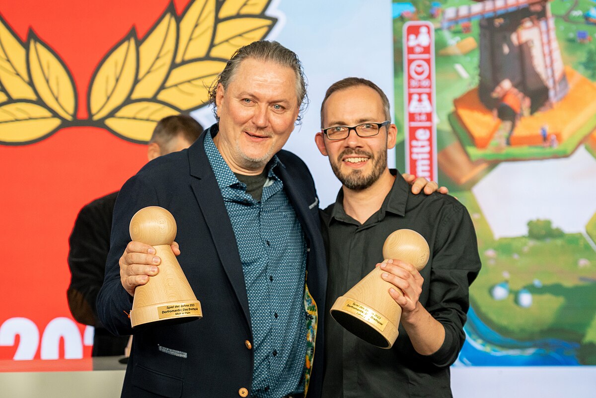 Photo of Dorfromantik designers Michael Palm and Lukas Zach, holding awards at Spiel des Jahres ceremony