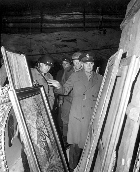 Black-and-white photograph of General Dwight D. Eisenhower in a German salt mine with looted paintings visible in foreground