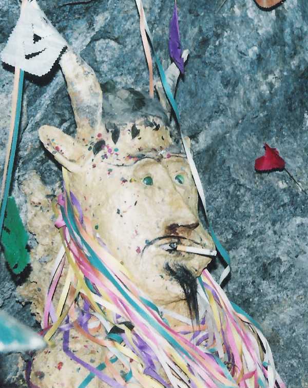 El Tio statue in Potosí with a cigarette in its mouth and colorful streamers on its head