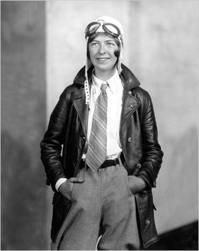 Black and white photo of Elinor Smith wearing a tie, leather jacket, and aviator hat with goggles