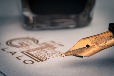 Close-up photo of worn fountain pen against gold-embossed stationary