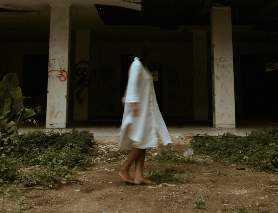 A woman in a white dress with her face covered by her hair