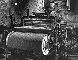 A black and white photo of a man working at a loom