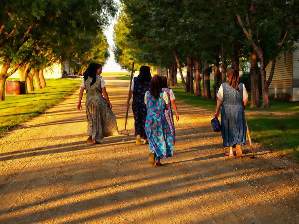 Color photograph of Hutterite women walking down a road during sunset