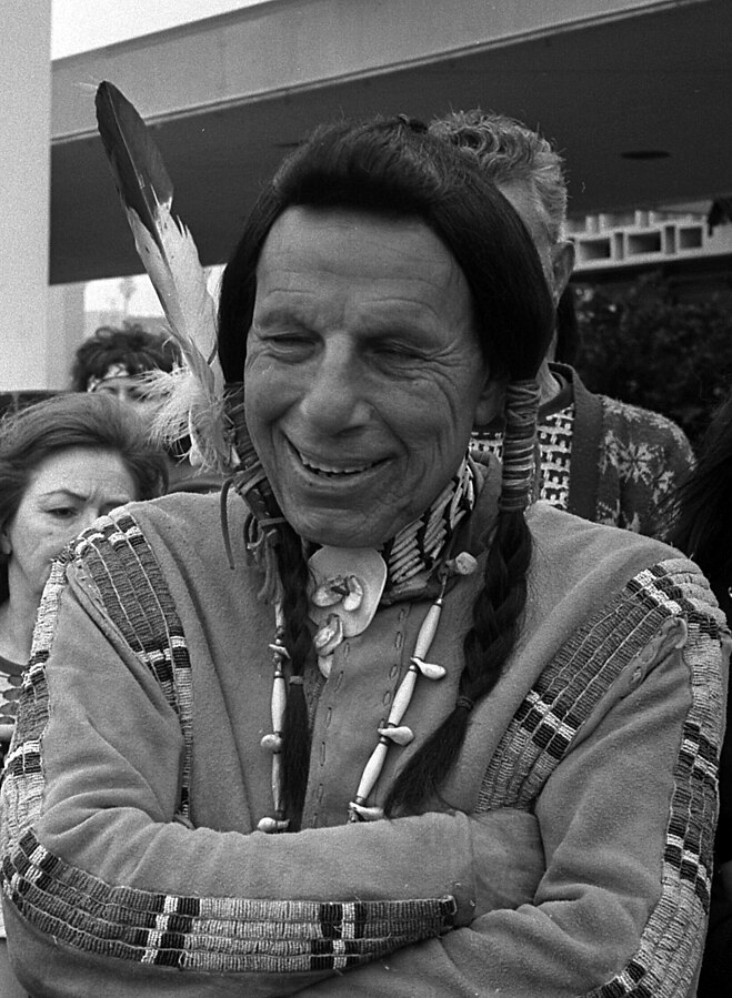 Black and white photo of Iron Eyes Cody in Native American headdress