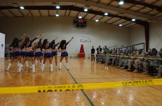 photograph of cheerleaders performing for soldiers in a gym