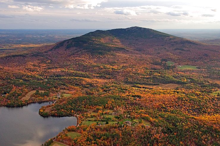 A scenic view overlooking trees with colorful leaves and Mount Monadnock