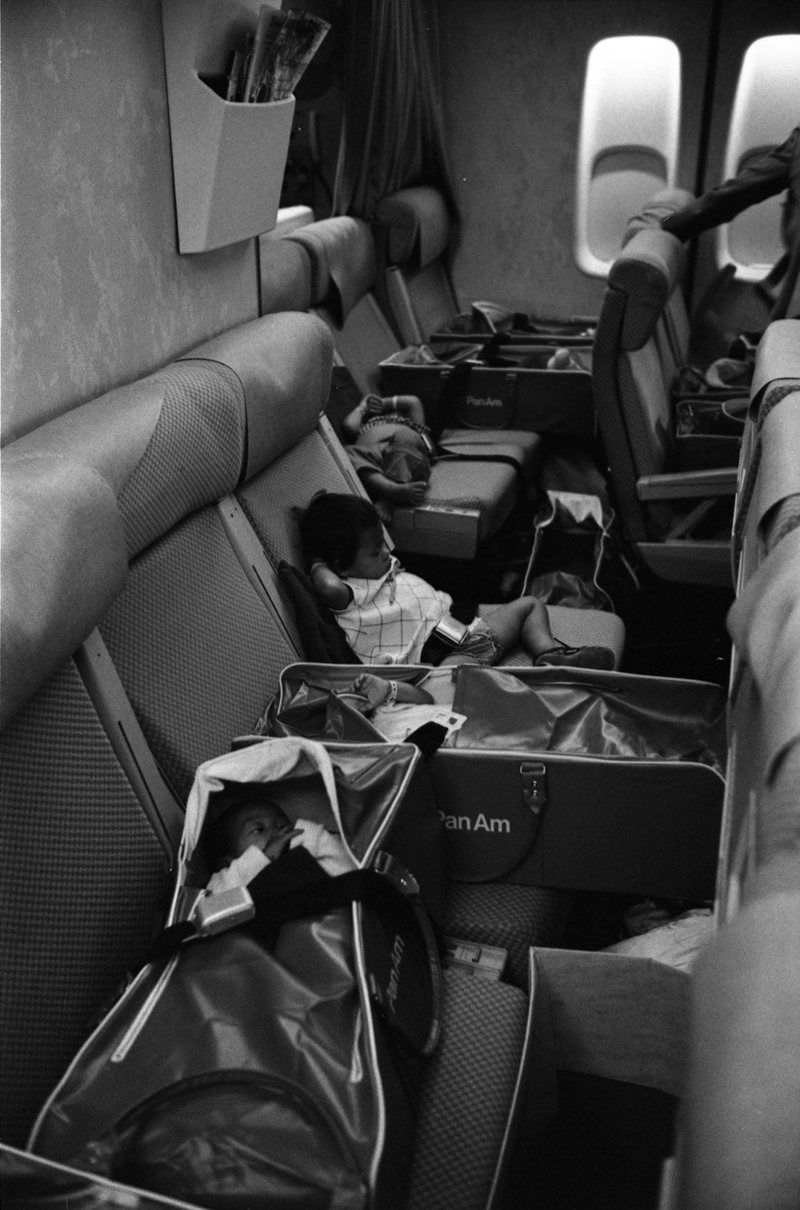 Vietnamese babies resting in Pan Am duffel bags on an airplane