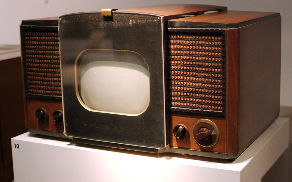 Old RCA television with small screen and a speaker on either side, encased in brown wood paneling