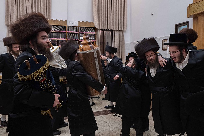 Simchat Torah celebration in a synagogue, with participants holding scrolls and dancing