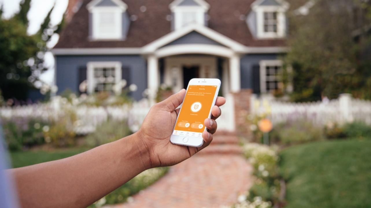 Hand holding a cellphone outside of a house