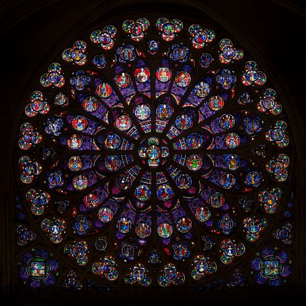 A circular stained-glass window of concentric circles, similar in form to the North Rose Window but with more reddish and bright violet hues