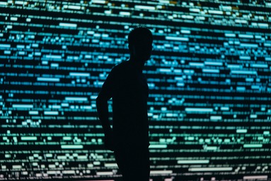 A silhouette of a man in front a computer