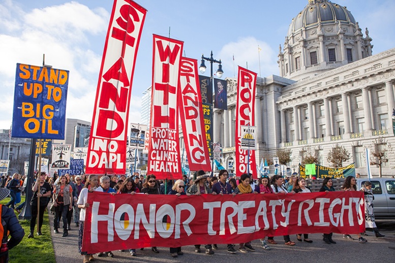 Protesters marching with signs saying Stand Up to Big Oil and other slogans