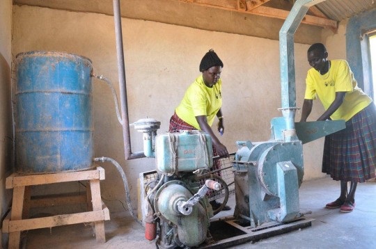 Ugandan women working on machinery provided by UNDP