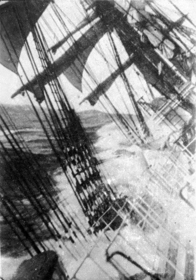 Black-and-white photographic image taken from a ship sailing near Cape Horn during a storm, tilted and partially submerged in waves
