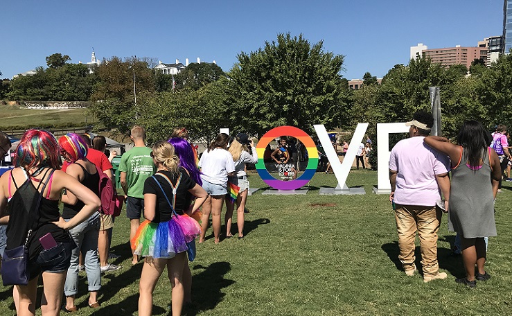 Crowd of people standing around a rainbow LOVE sign at Virginia Pridefest