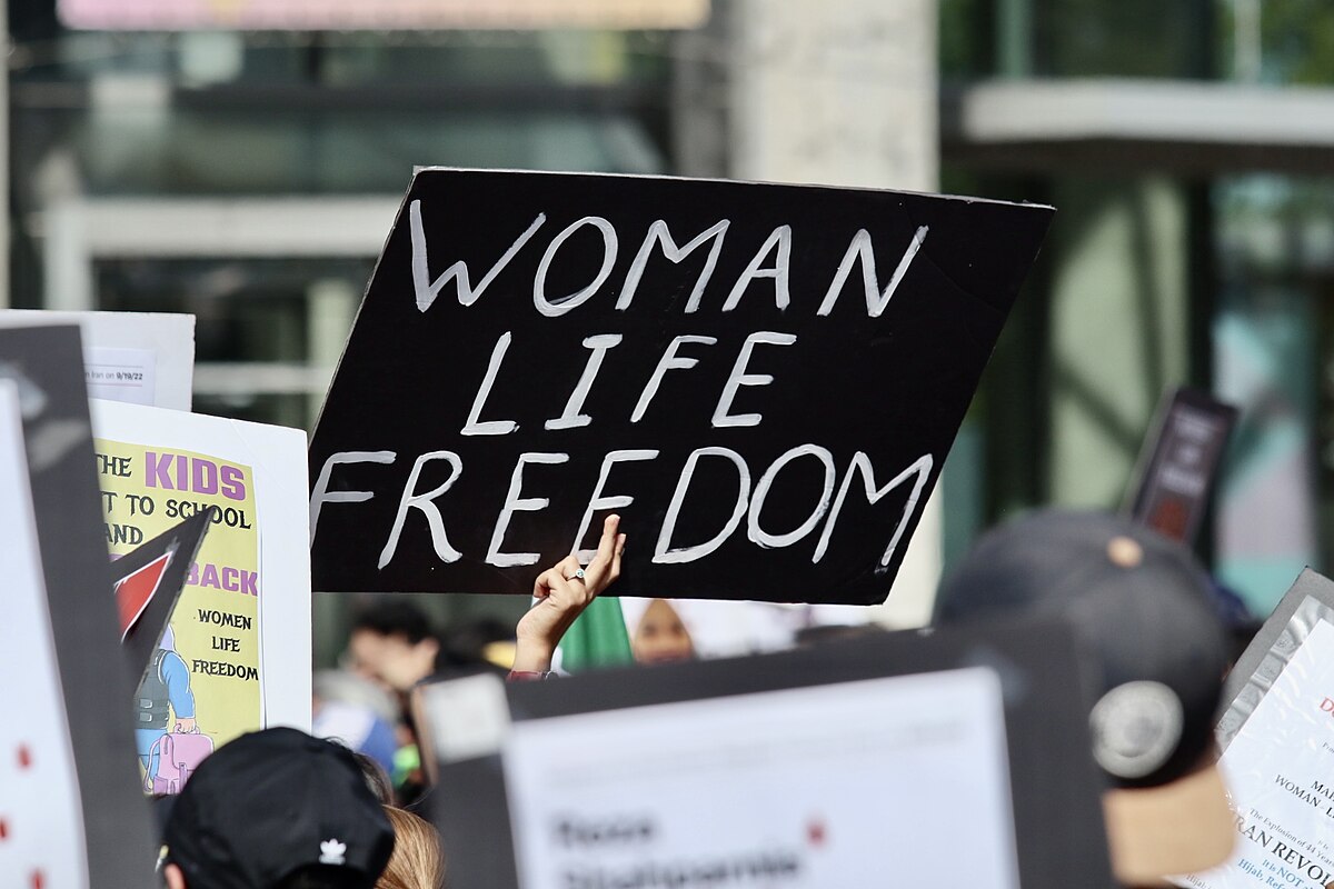 Photograph showing Woman, Life, Freedom sign held above crowd of protestors