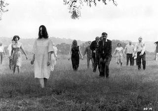 Black-and-white film still of zombies walking through a field